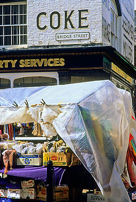 ENG: Thames & Chilterns Region, Oxfordshire, Upper Cherwell Valley, Banbury, Thursday Market. Stall, crowds in Market Place, in front of 19th C. collier. Sign: "COKE" [Ask for #243.116.]
